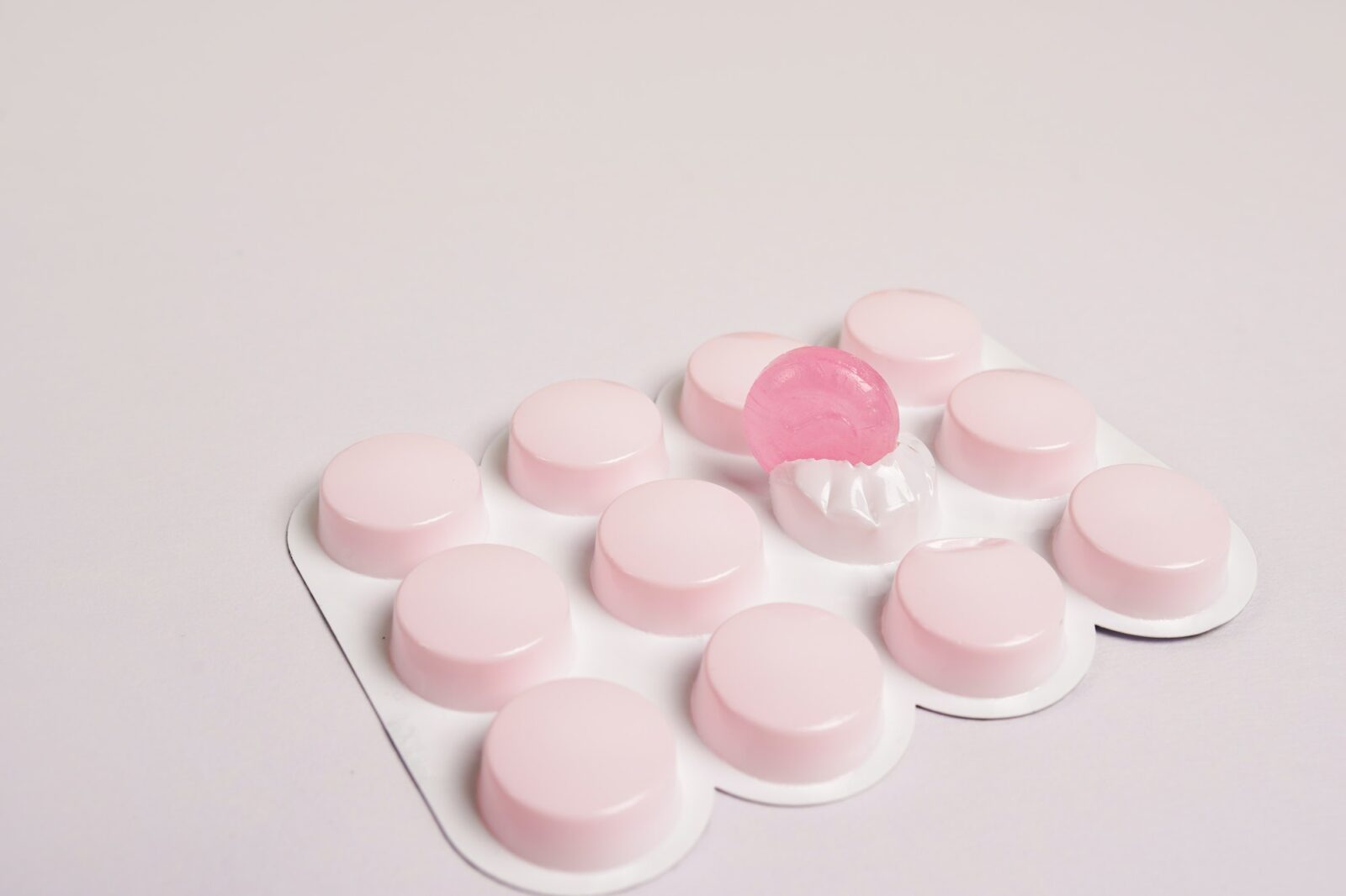cough lozengers over white background, pink pills